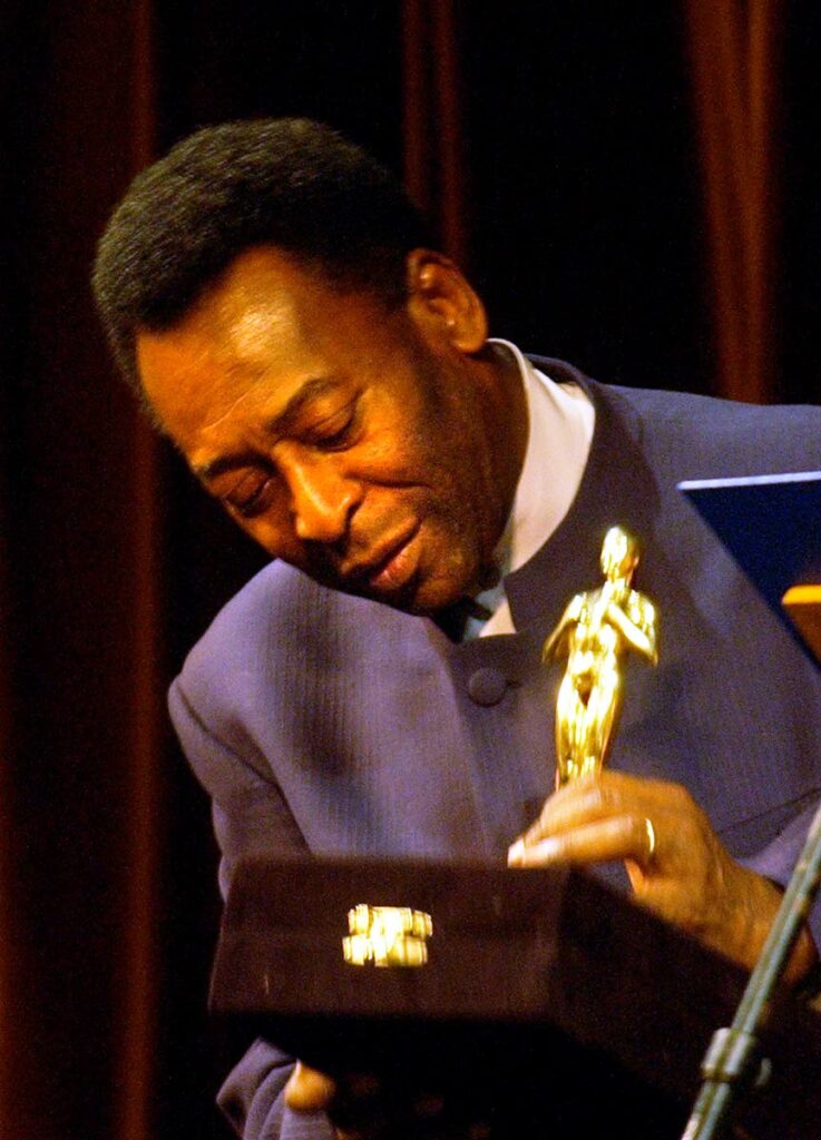 In this file photo, Brazilian football legend Pelé looks at a statue given by the Rio de Janeiro Gov. Rosinha Matheus, at the Municipal Theater in Rio de Janeiro,on June 21, 2004. The recognition was given during the premier of the movie 