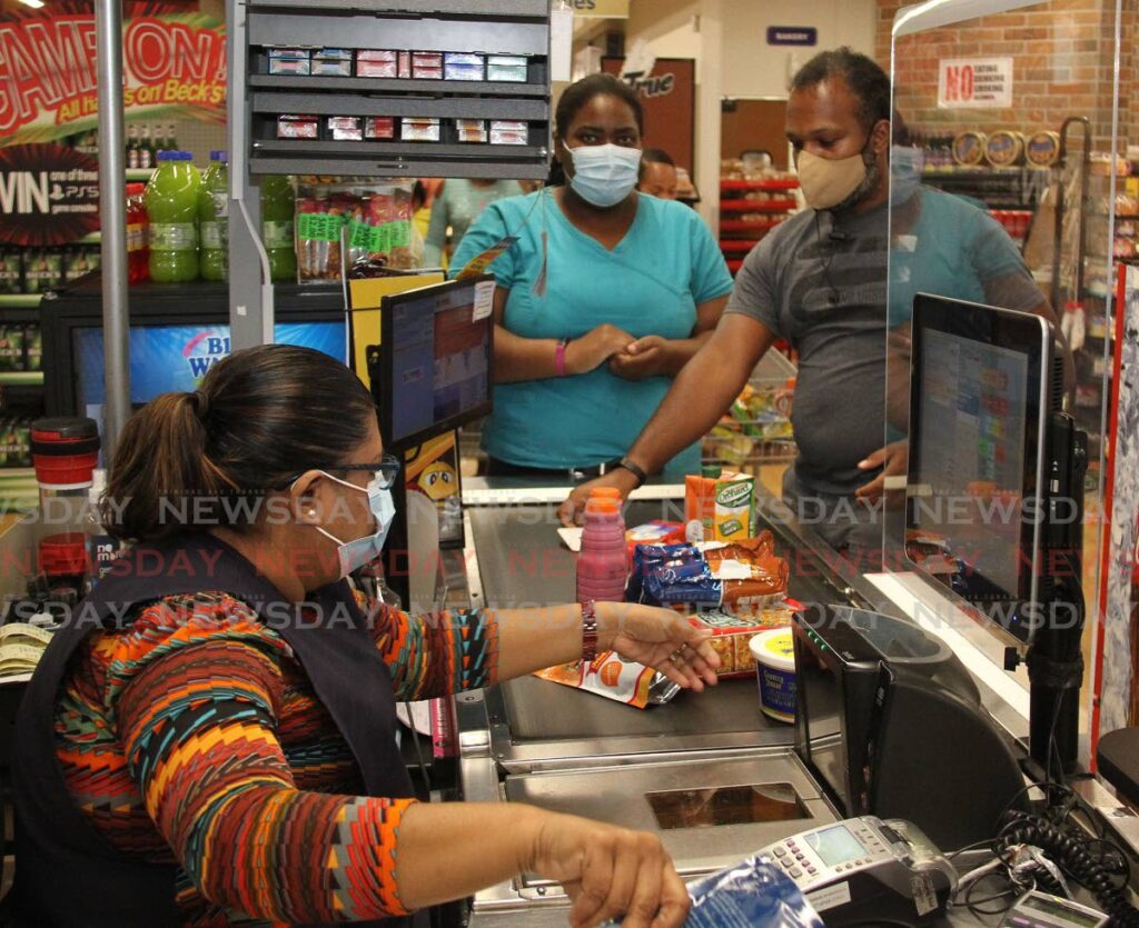 File photo: Customers pay for their groceries at a supermarket in Arima.  