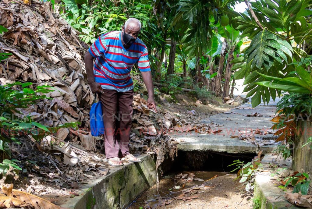 Bishop Innis Edwards shows a drain filled with silt and other debris at Depot Road, Castara, Tobago last year. File photo 