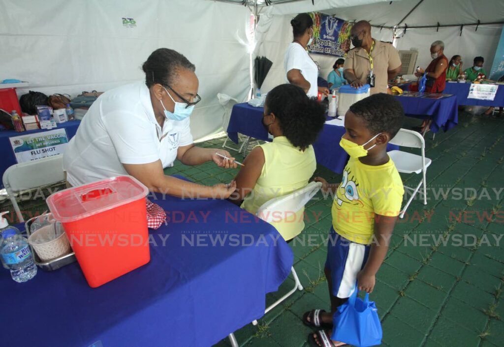 NEW DRIVE: The Ministry of Health is relaunching its national covid19 and flu vaccination drive from this Friday. In this file photo, district health officer Mary Chandler admisters an influenza vaccine to a woman during an SWRHA health fair in San Fernando back in November.  