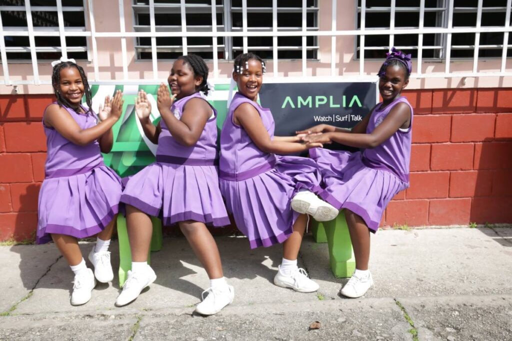 Students of the Sangre Grande SDA Primary School have fun during break-time on benches sponsored by Amplia. - 