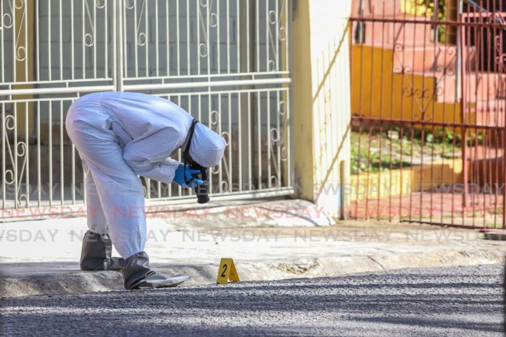 A crime scene investigator photographs evidence at the site where Isaiah Commissiong was shot dead at Clifford Roach Lane, La Horquetta on December 25, 2022. File photo by Jeff K Mayers
