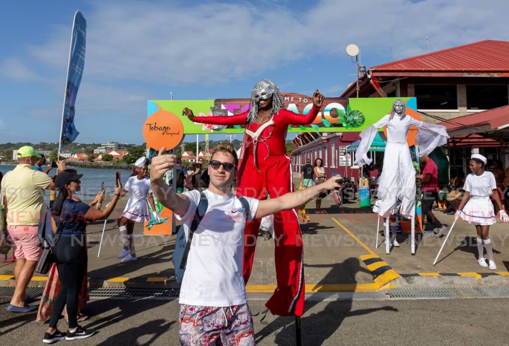 A visitor takes a selfie with a moko jumbie after arriving on a cruise ship in Scarborough on Monday.
