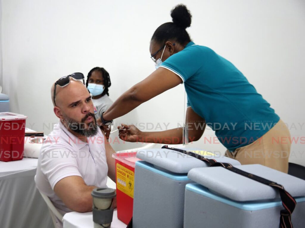 A nurse gives the covid19 booster to Nicholas Roger at Starlite Shopping Plaza, Diego Martin on Saturday. - SUREASH CHOLAI
