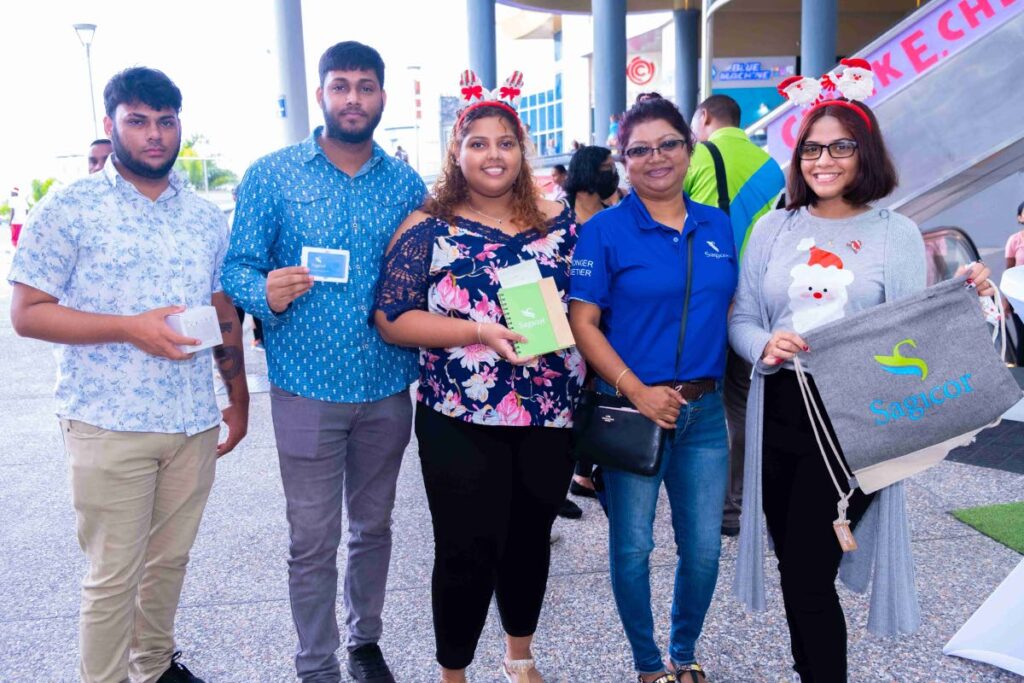 Sagicor adviser Anjanie Babwah-Seemungal from the Brian Dookeran agency poses for a photo with C3 shoppers holding their tokens from the Spin the Wheel.