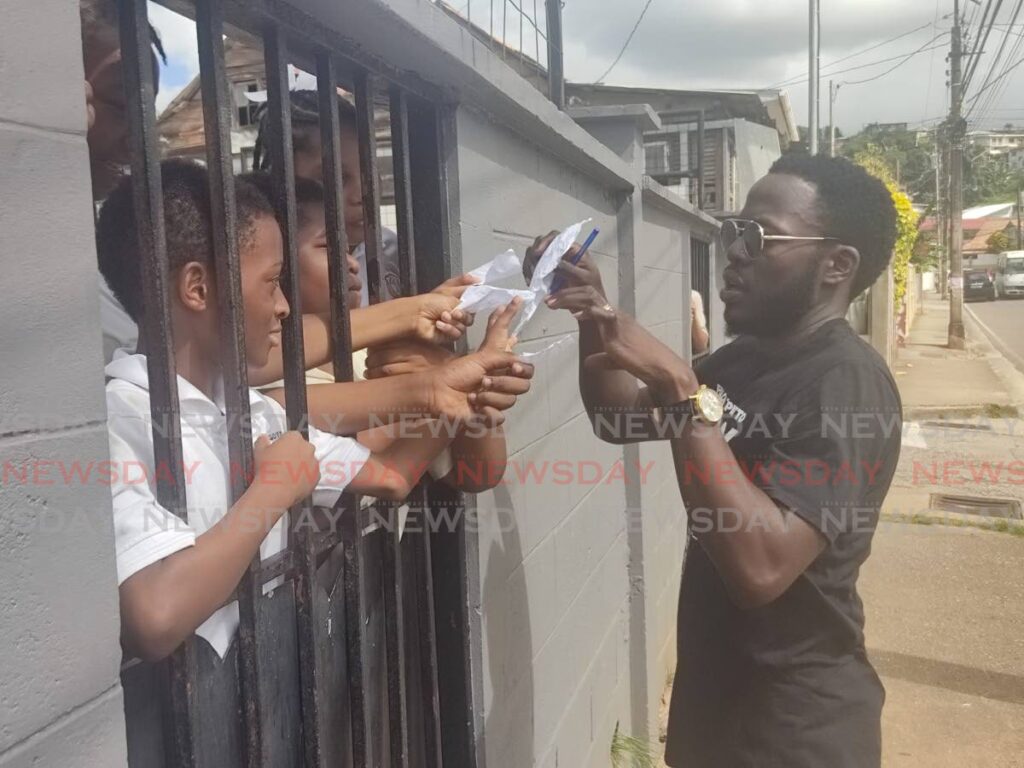 Soca artiste Erphaan Alves signs autographs for students while leaving the Belmont Government Primary School on Friday afternoon.  - Shane Superville