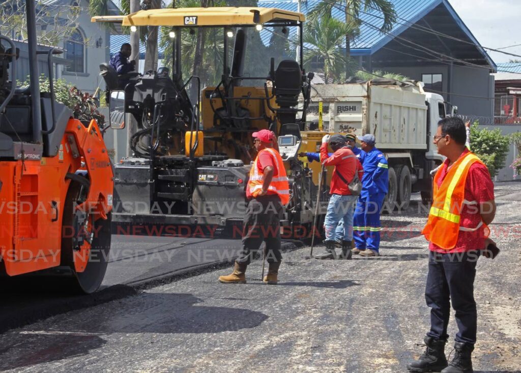 Minister of Works and Transport Rohan Sinanan, right, observes road repair contractors as they spread a fresh layer of asphalt on Suchit Trace, Penal on Saturday. - Marvin Hamilton