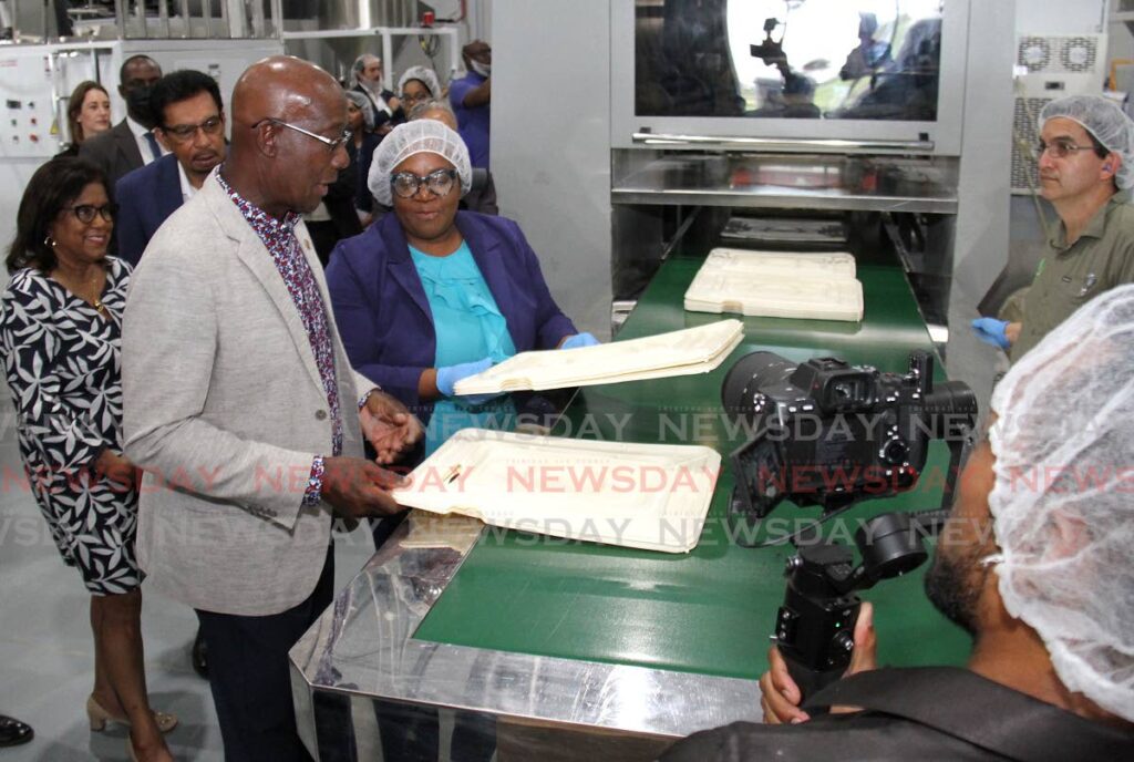 PriceSmart health safety, environment and quality lead Shelly-Ann Alexis-Anderson shows Prime Minister Dr Keith Rowley the domes for cake trays during the opening of the company's sustainable solution plants at Point Lisas Business Park, Couva.  - AYANNA KINSALE