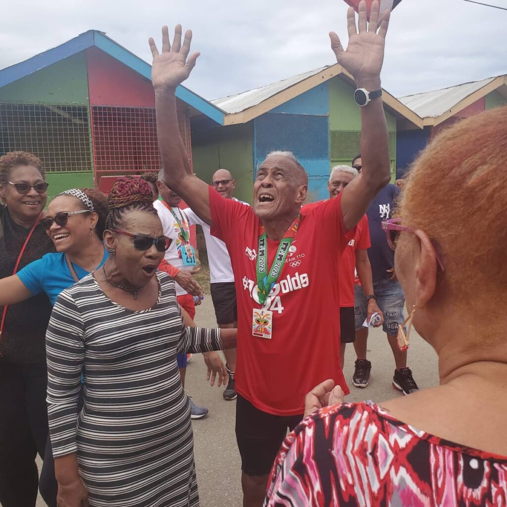 Derrick McIntyre, 84, celebrates completing the 26.2 mile TT Olympic Committee marathon walk at the Queen's Park Savannah, Port of Spain, on Sunday.  - 
