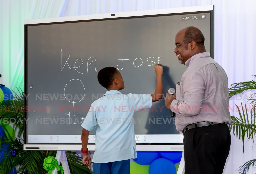 IdeaHub expert Kenneth Atwell, right, uses a Speyside Secondary student to demonstrate the IdeaHub can be used as blackboard in the classroom, at its unveiling and handing over at Speyside Secondary School on Monday. - David Reid