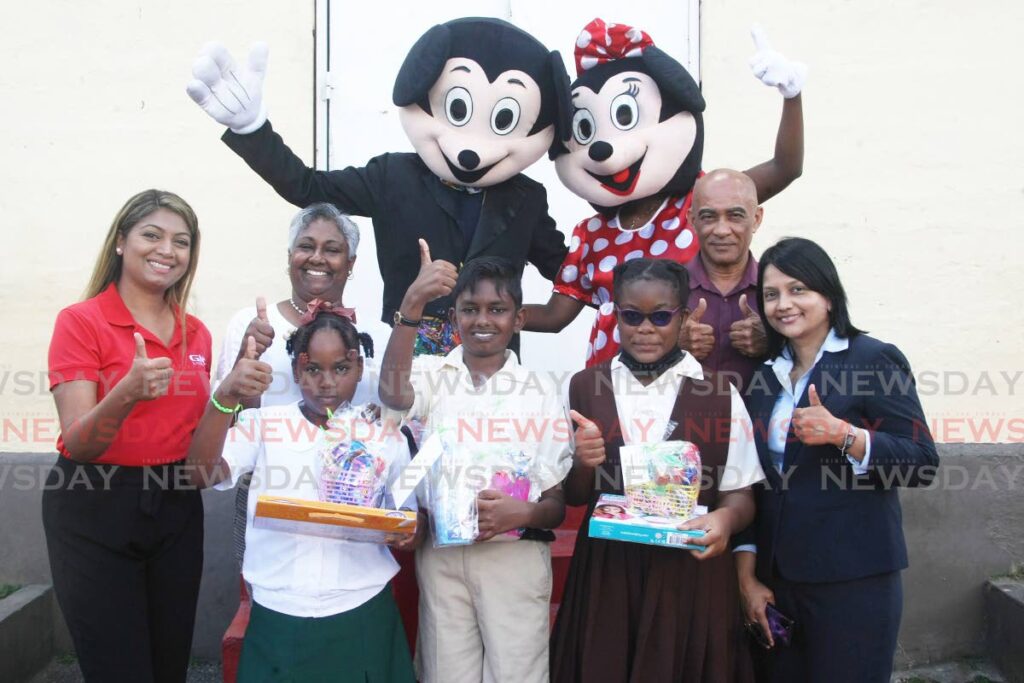 KIND essay-writing competition winner, Damascus Siewnarine, centre, celebrates with sponsors, teachers, consolation prize winners, and Minnie and Mickey. Photo by Lincoln Holder