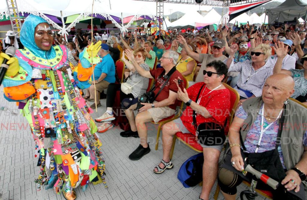 Tourists wave to the live music of Olatunji Yearwood (at back on left), while being entertained by a pierrot grenade, at Carnival Village, Queen's Park Savannah, Port of Spain on February 4. - File photo/Angelo Marcelle