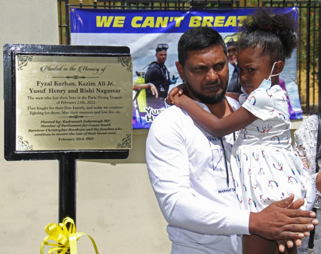 IN THE MEMORY:
Christopher Boodram holds his daughter Ciara near the plaque bearing the names of Fyzal Kurban, Kazim Ali Jr, Rishi Nagassar and Yusuf Henry which was unveiled on Thursday in Couva, two days short of the first anniversary of the death of the men. Boodram was the lone survivor in the Paria drowning tragedy.
PHOTO BY MARVIN HAMILTON - 