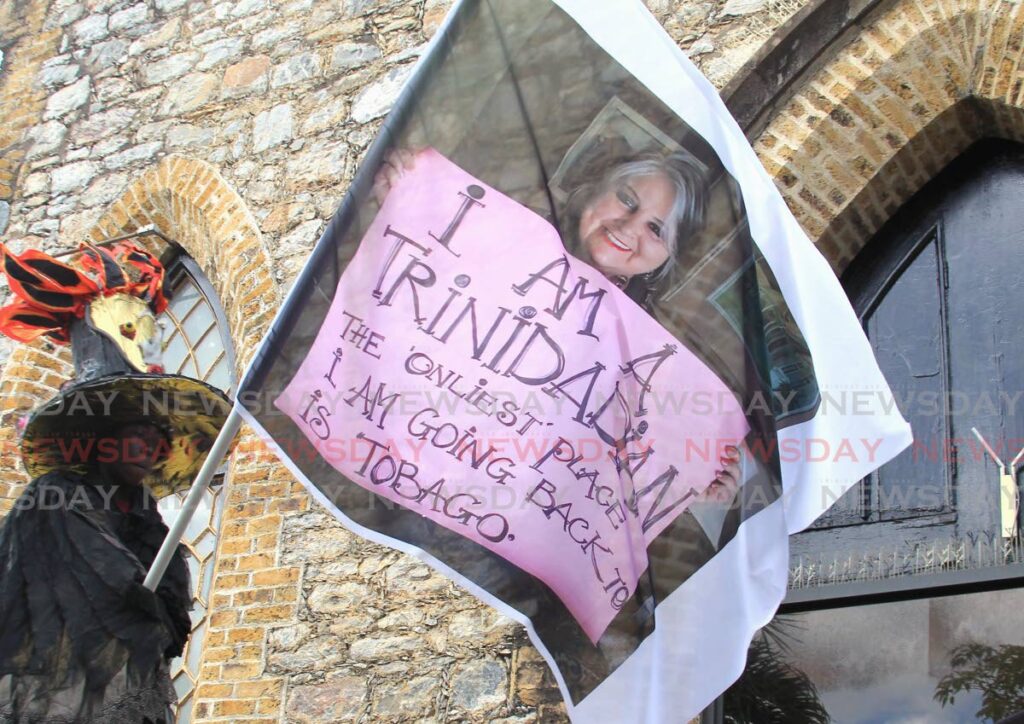 A moko jumbie waves a flag with a picture of Kathryn Ann Baxter Stollmyer-Wight during her funeral at the All Saints Anglican Church, Queen's Park West, Port of Spain, on Monday. In the picture, StollmeyerWight is holding a sign that says, 