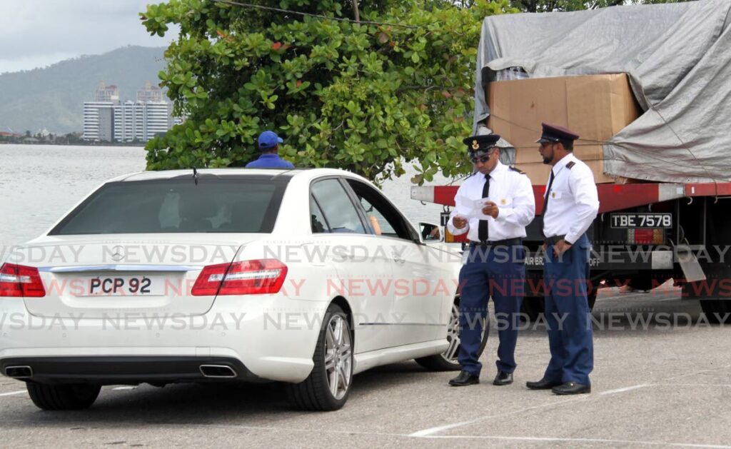 In this file photo, licensing officers issue a ticket during a roadblock exercise on  the Audrey Jeffers Highway, St James. - 
