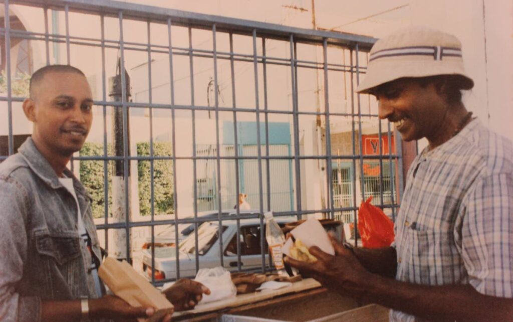 Joe Rampersad, right, wraps doubles for a customer at Park Street, Port of Spain. The photo was taken in the 1980s. - 