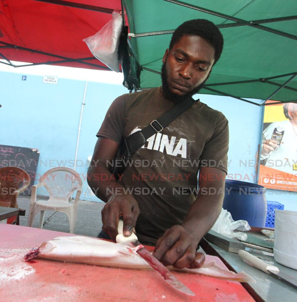 Fish vendor and fisherman Jovan Castillo cleans a shark at his stall on George Street, Port of Spain on Wednesday.  - Angelo Marcelle