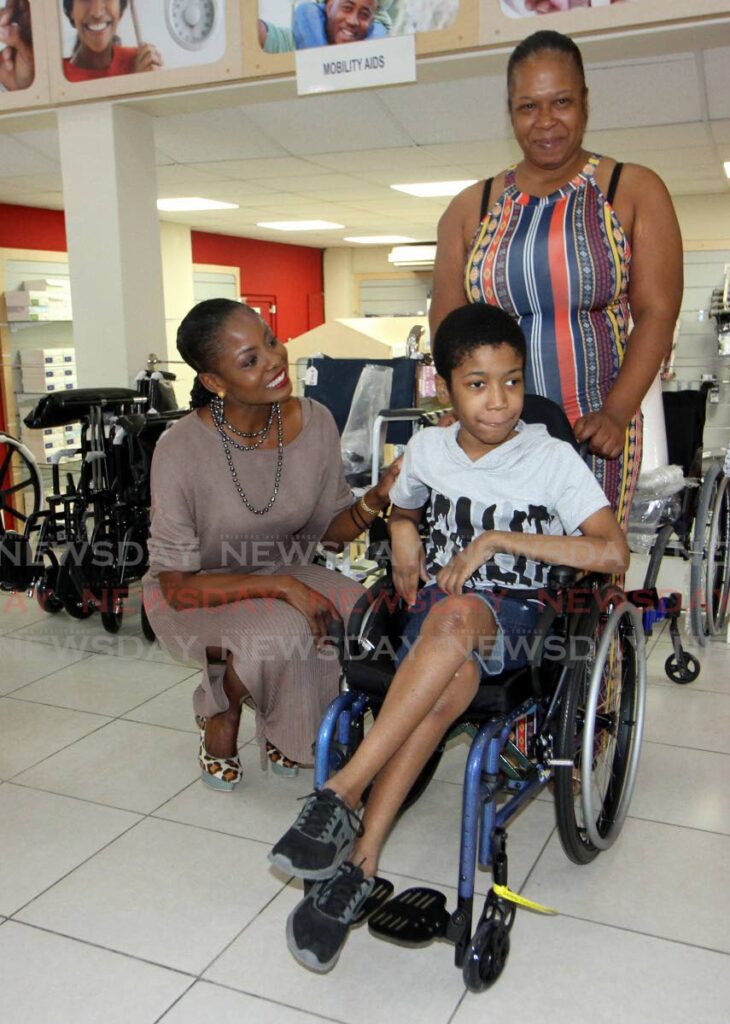 Ma Pau CEO Wendy Fitzwilliam, left, presents  Jayden Charles, 13, and his mother Colleen Edwards with a wheelchair at  AA Laquis, Ariapita Avenue, Port of Spain on Friday. - Angelo Marcelle
