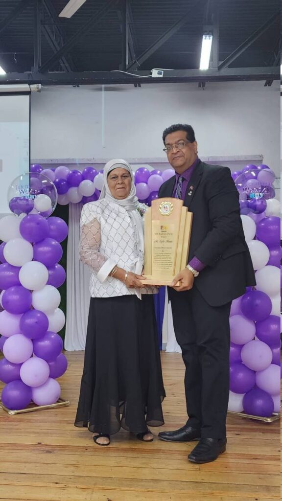 Mrs C Hosein, left, collectes an award on behalf of daughter Safia Hosein from Mayaro MP Ruston Paray. - 