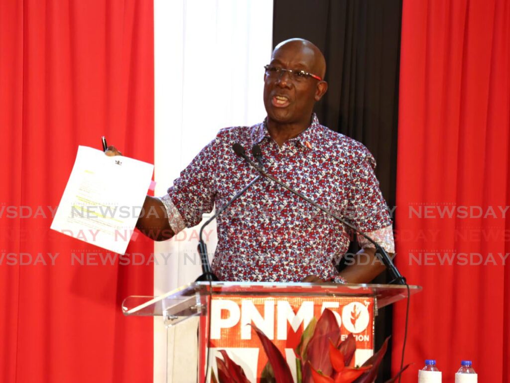 Prime Minister Dr Keith Rowley shows a document which he read from during the PNM’s meeting on Thursday night at the Barataria Community Complex. Photo by Roger Jacob