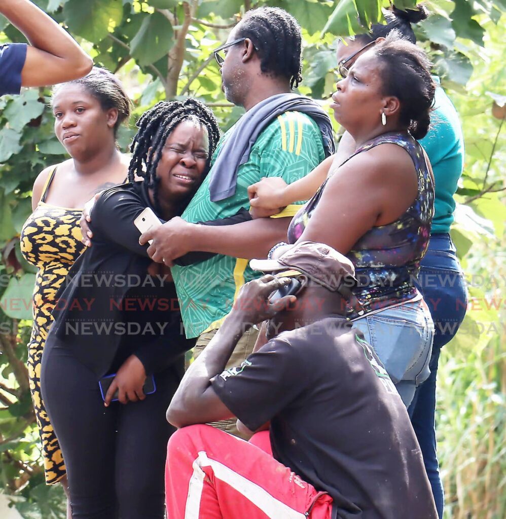 TEARS FOR BRANDON: Relatives at the construction site off the Cascade Main Road on Friday after Brandon Victor was gunned down. Photo by Roger Jacob 