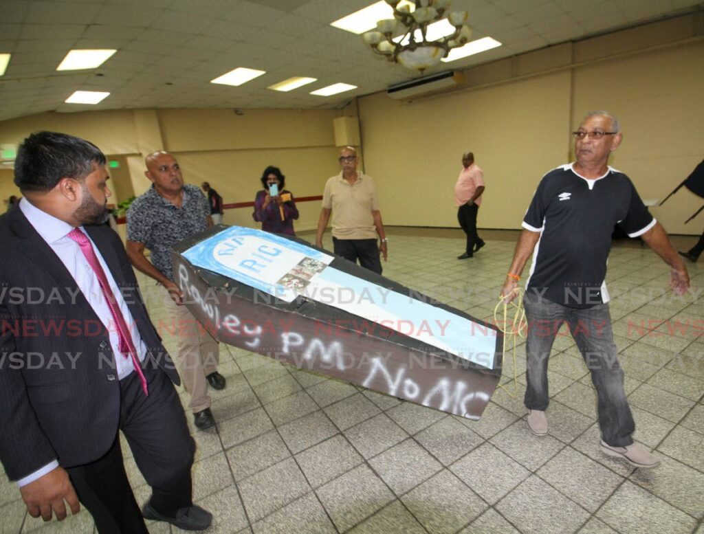 Chaguanas residents carry a coffin to a consultation held by the RIC at Centre Point Mall, Chaguanas on Wednesday. 
Photo by Angelo Marcelle -