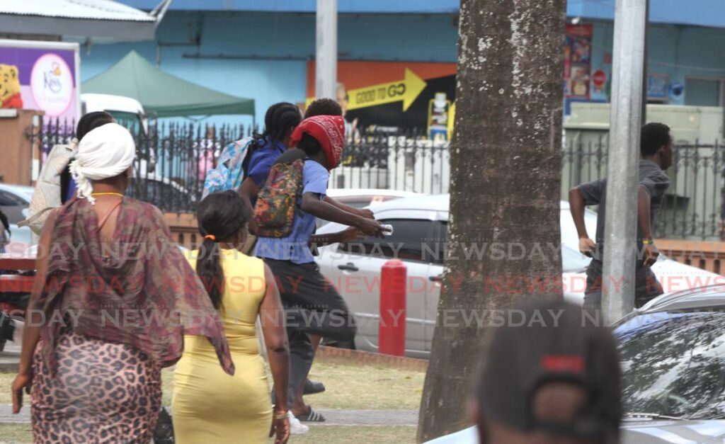 A group of schoolboys throw bottles and other objects at a rival group of schoolboys during a violent confrontation on Independence Square, Port of Spain, on March 17 as pedestrians look on. - NEWSDAY PHOTOGRAPHER