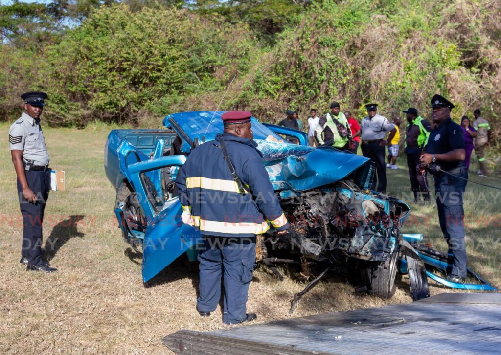 Police and fire officers at the scene of a fatal accident which claimed the life of Denbert Alfred along the Claude Noel Highway, Lowlands on Tuesday. - Photo by David Reid