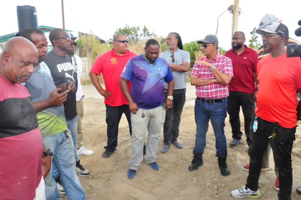 Minister of Works and Transport Rohan Sinanan, in plaid shirt, speaks with taxi drivers from East Trinidad on Saturday.