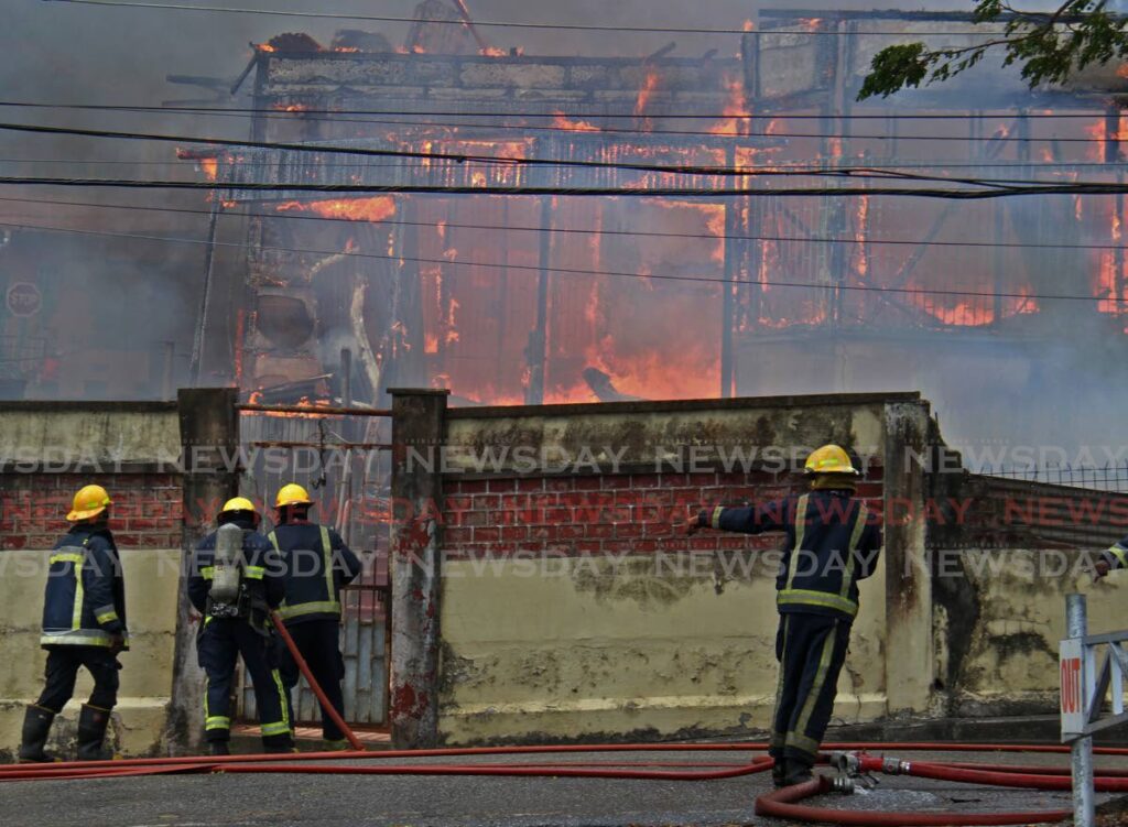 FIRE: Firemen at the scene of a blaze which completely gutten a 100-year-old wooden house at the corner of Chacon and Penitence streets in San Fernando on Sunday. PHOTO BY MARVIN HAMILTON - 