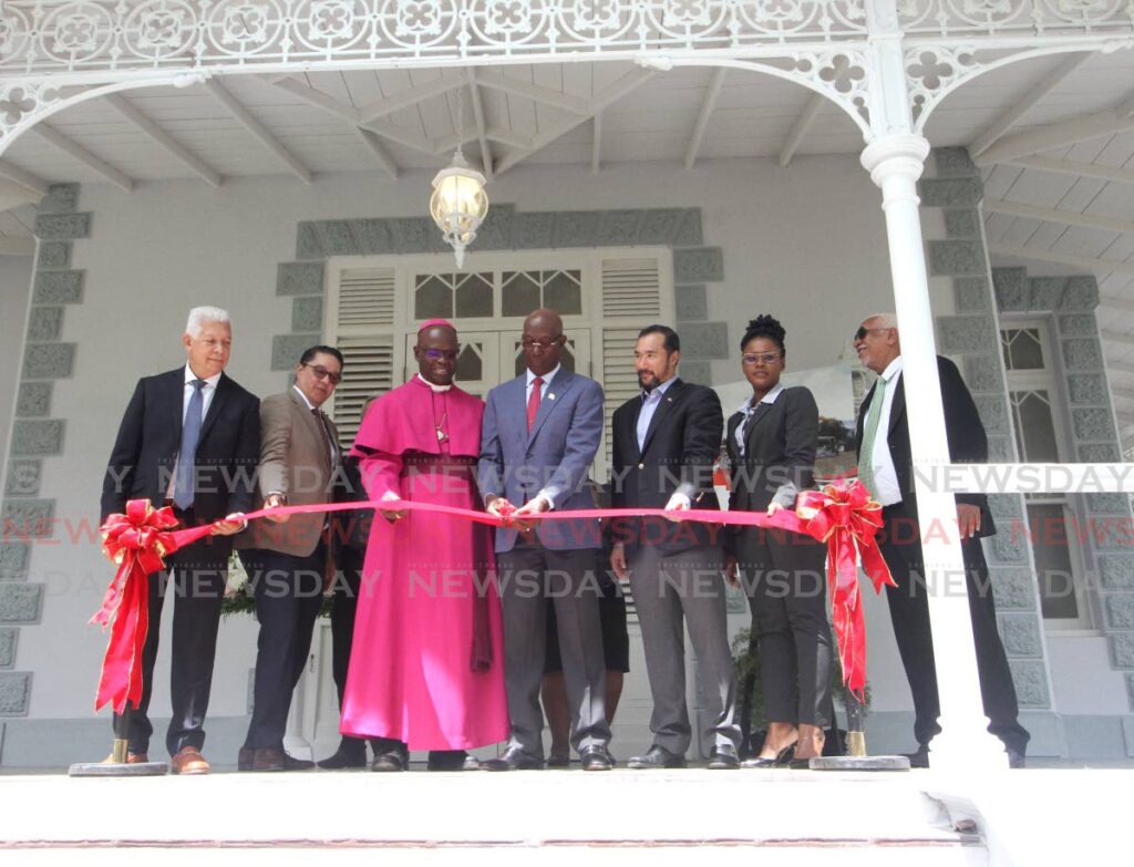 The Prime Minister cuts the ribbon during the handing-over of Hayes Court, Port of Spain. From left: Port of Spain Mayor Joel Martinez, Communications Minister Symon de Nobriga, Bishop Claude Berkley, Minister of Energy and Energy Industries Stuart Young, Udecott CEO Tamica Charles-Phillips and Udecott chairman Noel Garcia. - Photo by Angelo Marcelle