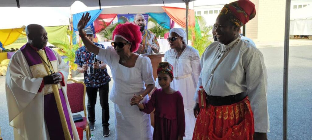 Opposition Leader Kamla Persad-Bissessar, escorted by a child, arrives for Spiritual Shouter Baptist Liberation Day celebrations at the Moruga Multi-Purpose Youth and Sports Facility at Fifth Company, Moruga on Thursday. - 