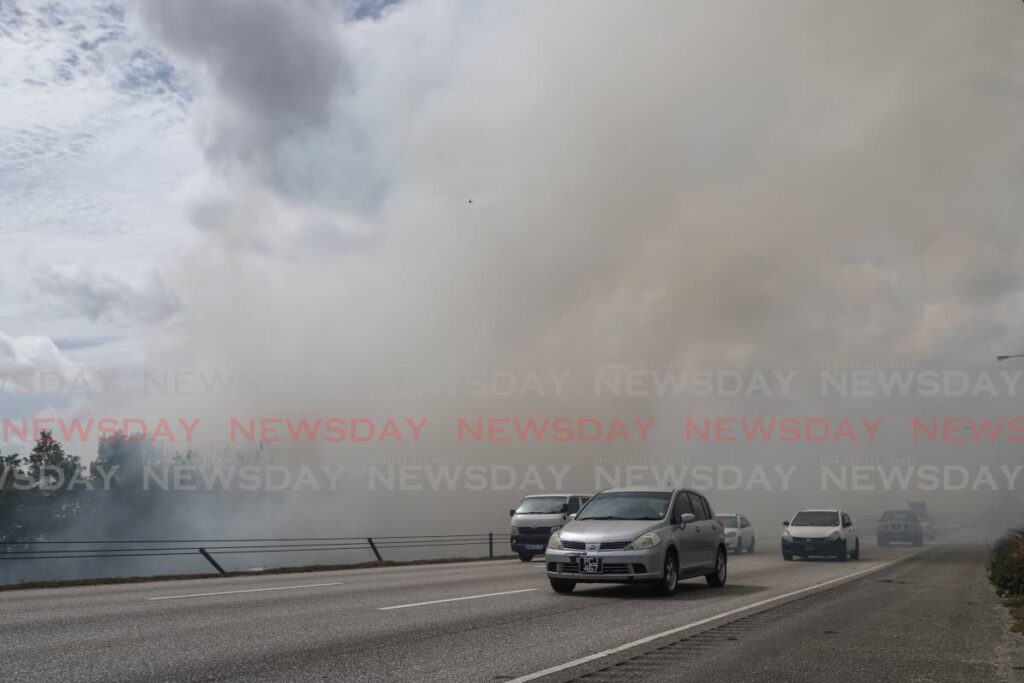 Drivers emerge from blinding smoke along the Uriah Butler Hghway, Caroni, caused by a bush fire on April 13. - JEFF K MAYERS