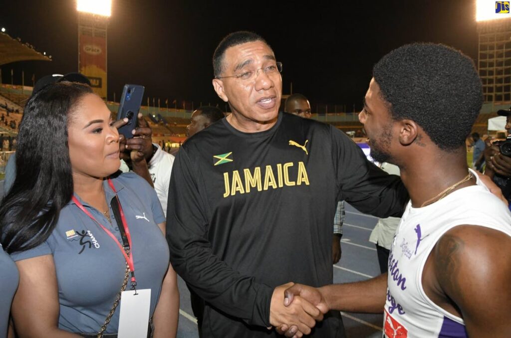 Jamaican Prime Minister Andrew Holness (centre), congratulates Kingston College's sprinter, Bouwahjie Nkrumie (right), after he won the Class One 100-metrer race in record-breaking 9.99 seconds at the Boys and Girls’ Championship (Champs) at the National Stadium on March 29. Looking on is TT's Minister of Sport Shamfa Cudjoe. - Jamaica Information Services 