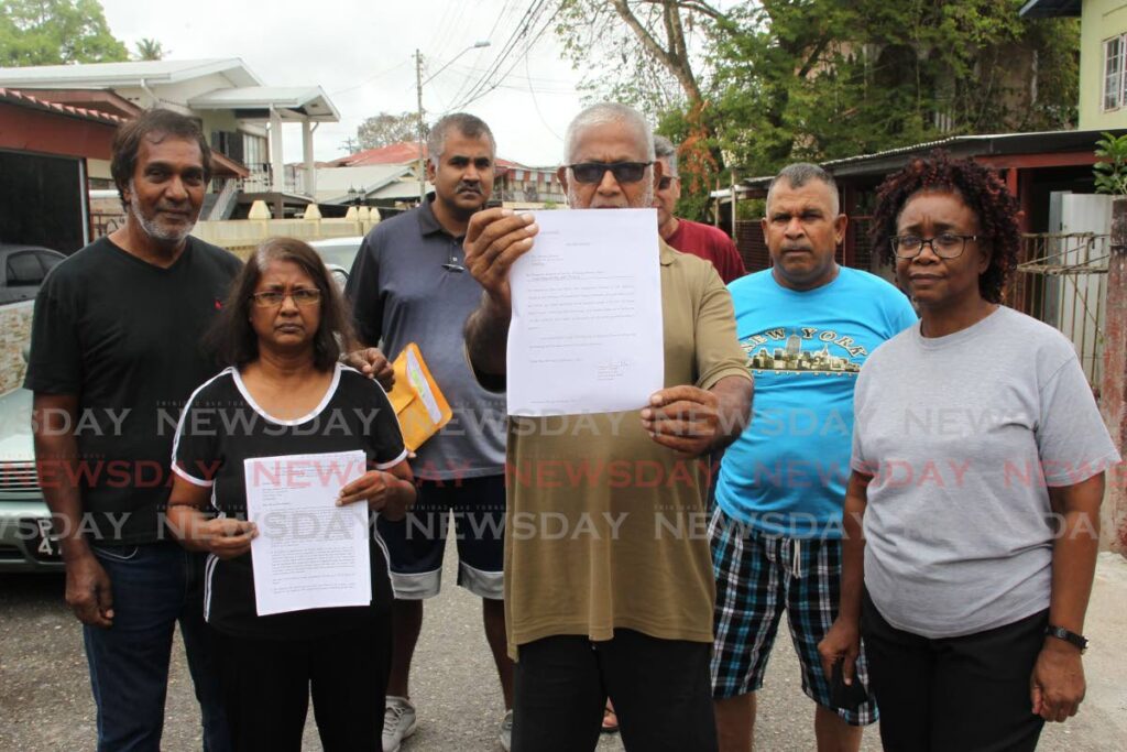 Resident Jimison Sinanan, centre, with other residents, shows a notice to quit by the Anglican Church given to residents of Milner Town in Couva to vacate the lands they have been occupying for almost 100 years. - Lincoln Holder