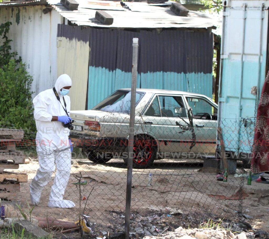 A crime scene investigator processes the area where two men were shot dead and a pregnant teenager wounded at Freeman Road, St Augustine on Wednesday. - ANGELO MARCELLE