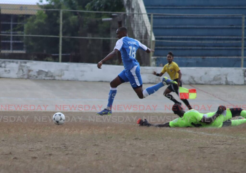 Reon Moore of Defence FC rounds Prisons goalie Osei Clarke to score in the TT Premier League at the Arima Velodrome, Saturday. - Roger Jacob