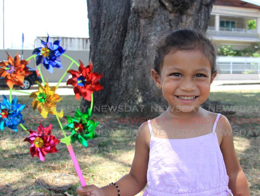 Sophia Mar plays with her windmill at the Easter bonnet parade and craft market at Siegert Square, Woodbrook.  - AYANNA KINSALE