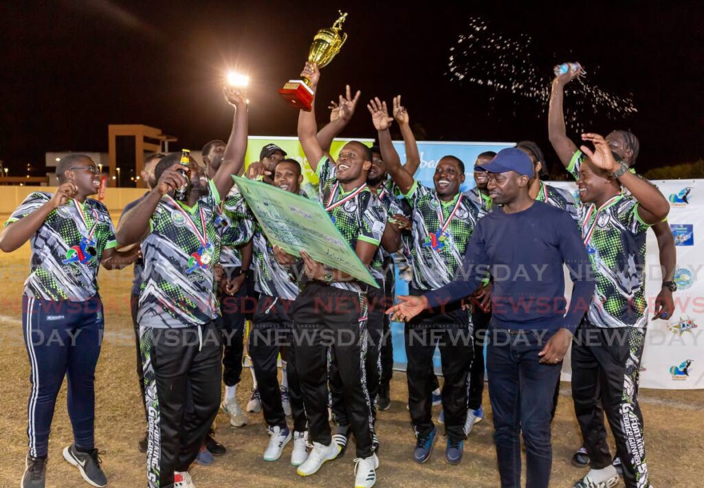 Fort King George Gunners celebrate their victory after receiving their cheque and trophy from Chief Secretary Farley Augustine, right, in the Chief Secretary Bago T10 Blast, at Cyd Gray Complex, Roxborough, Sunday.  - David Reid