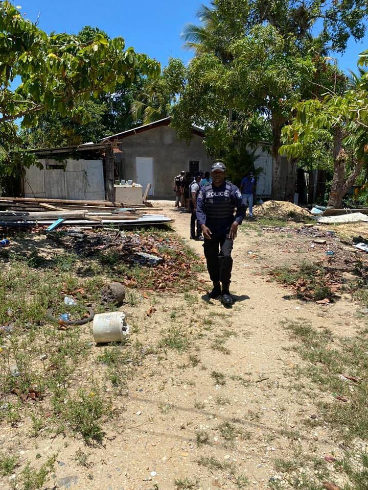 A policeman walks out of a yard during a confidence walkabout in Pinto Road, Arima, on Wednesday morning.  - Photo courtesy TTPS