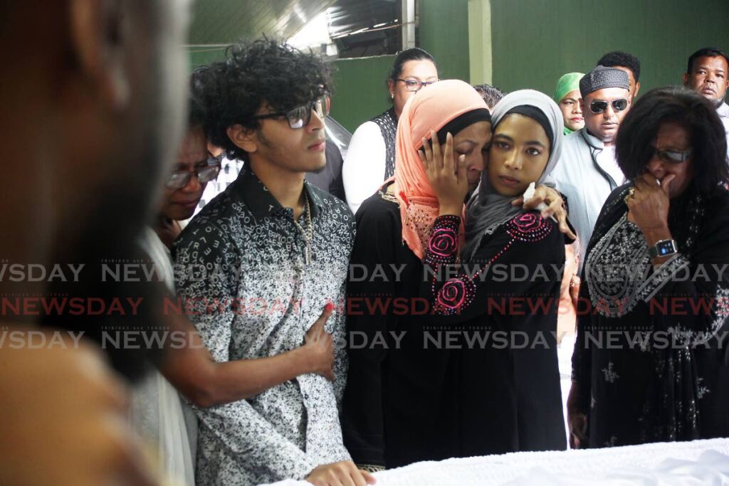 Raeesa Ali consoles her mother Resha Ali, while son Raed is consoled by a relative at the funeral of businessman Rishard Ali at Biljah Road Extension, Chaguanas on Saturday. - Lincoln Holder