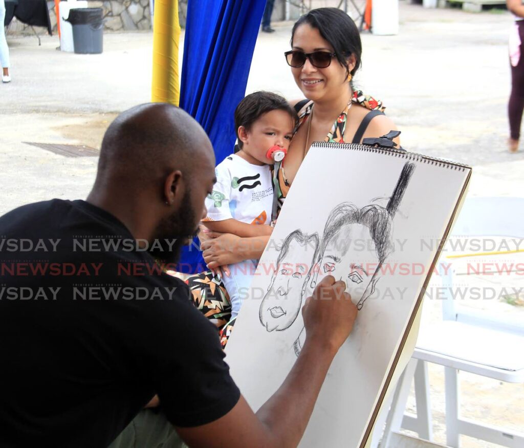 Artist Javaughn Forde does a charcoal drawing of Roma Dindial and her two-year-old son Jaxson Dindial, during the National Museum and Art Gallery World Art Day at the Port of Spain Museum, South Quay on Saturday. - AYANNA KINSALE