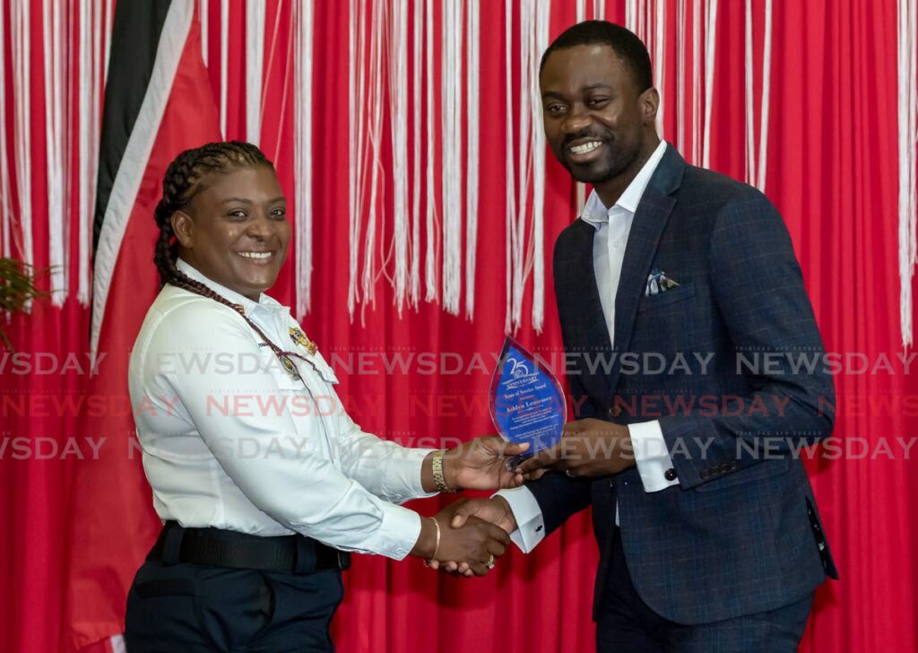 TEMA team leader Ashlyn Lemessee, left, receives an award from THA Chief Secretary Farley Augustine at TEMA's 25th Anniversary celebration and award ceremony at Shaw Park Complex, Tobago, on Monday. - David Reid