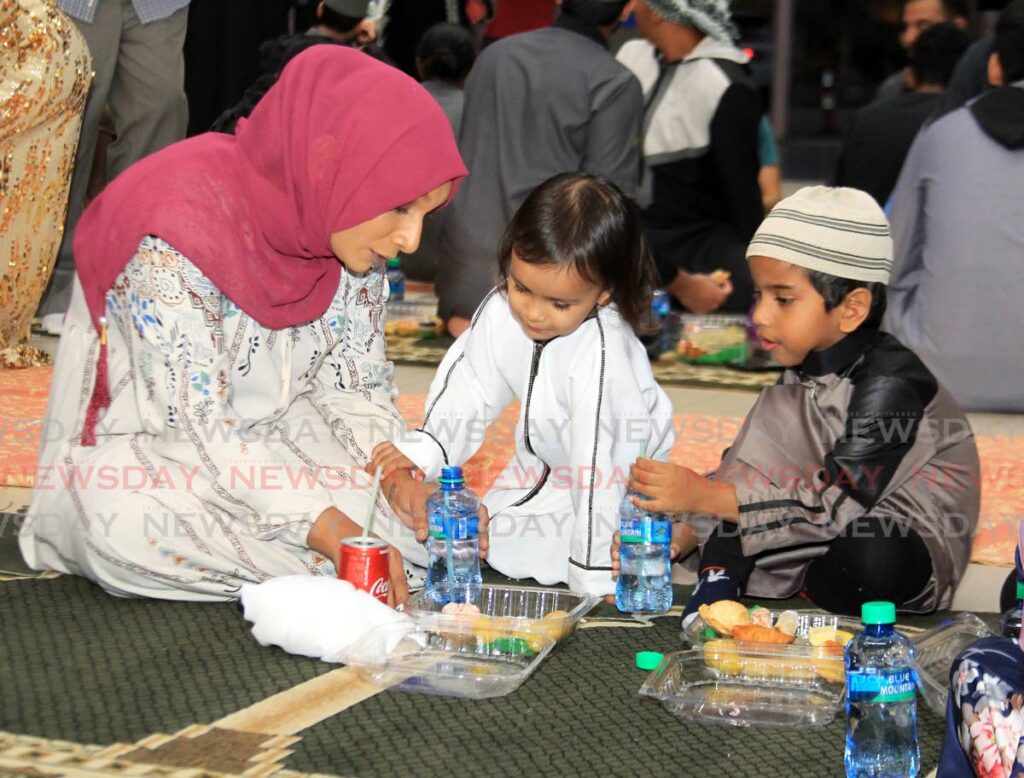 FAST IS OVER: Muslim faithful Hana Khan eats with her niece Hawwa, centre, and another youngster Kazim after the breaking of the Ramadan fast for the day on Tuesday at Gulf City Mall. PHOTO BY AYANNA KINSALE - 