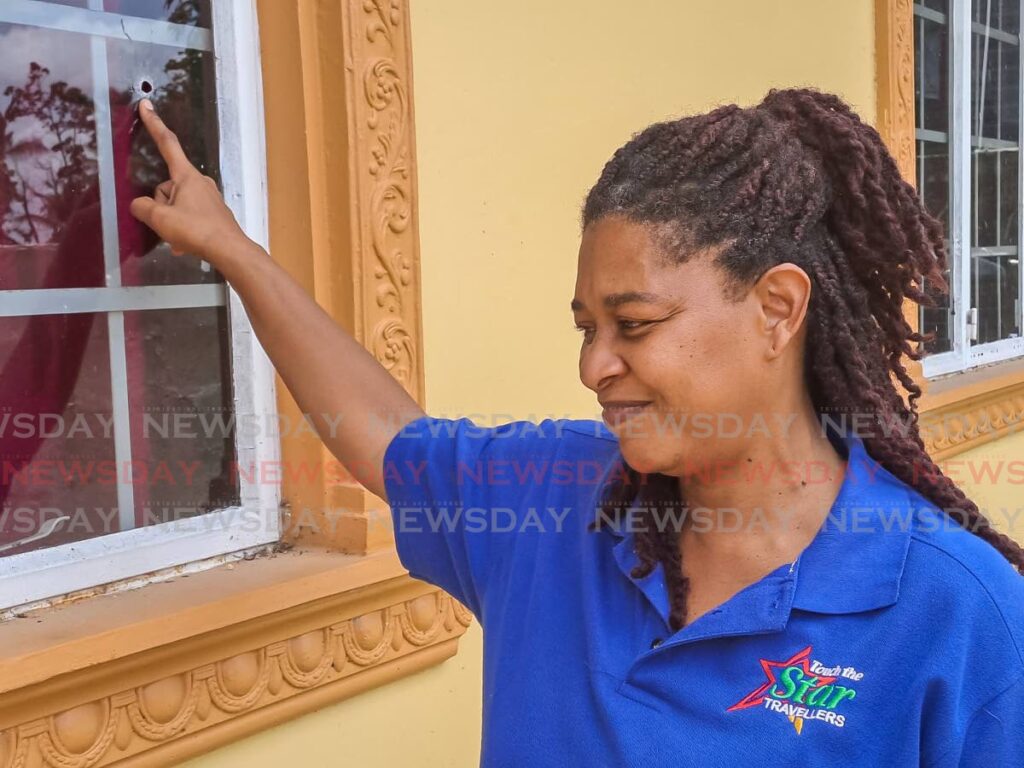 Michelle Saunders-Callender points to the hole in the window at her Trainline, Malabar, Arima home where a bullet penetrated before hitting and killing her sister Kernella on Tuesday night. PHOTO BY JENSEN LA VENDE - Jensen La Vende