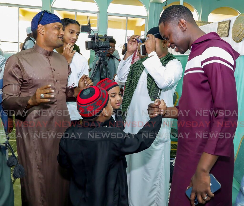 THA Chief Secretary Farley Augustine, right, greets two youngsters at Eid-ul-Fitr celebrations in Masjid al Tawbah Mosque, Lowlands, Tobag on Saturday. - Photo by David Reid
