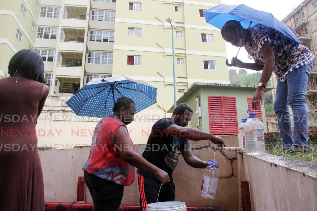 Olera Heights residents line up to fill containers of water because tenants on the upper floors are complaining of no water due to broken down pumps  - Photo by Lincoln Holder