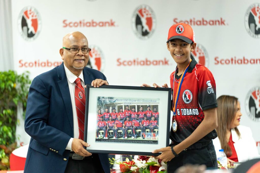 TTCB president Azim Bassarath receives a framed picture of TT title-winning U15 team from vice-captain Yasir Deen on Monday.  - Scotiabank