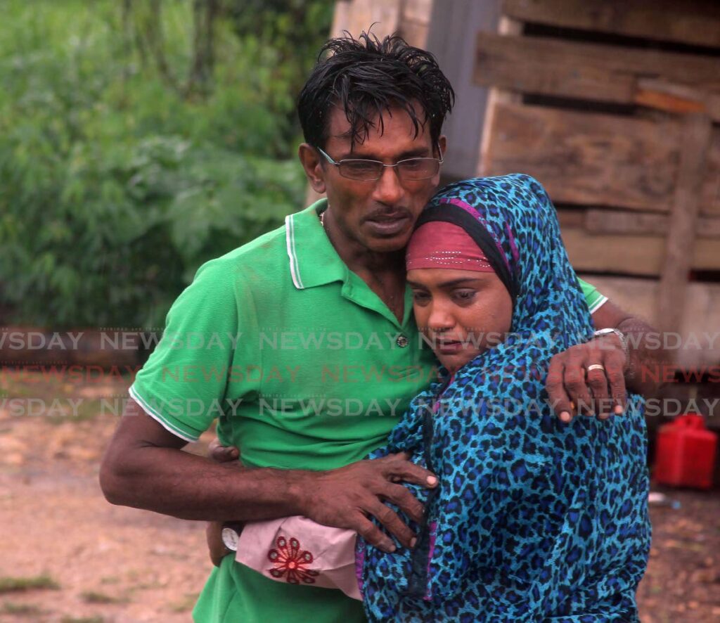 Asha Dajurlal and Radesh Rampersad, sister and father of murder victim Adesh Heeralal, console each other on Tuesday after he was killed near their Wilson Road, Penal, home on Monday night.  - Photo by Lincoln Holder