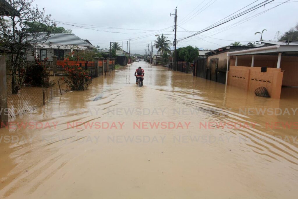 A man rides through floodwaters on Picton Street, Sangre Grande on Tuesday. - Photo by Angelo Marcelle